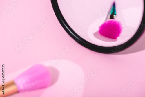 makeup brush with reflection in mirror on pink