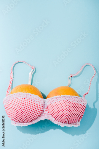 top view of bra with two oranges on blue with copy space, breasts concept