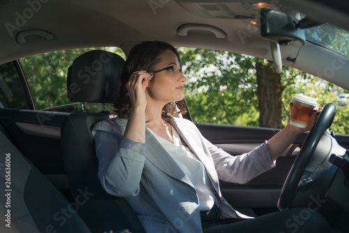 Beautiful businesswoman painting her eyelashes in a car