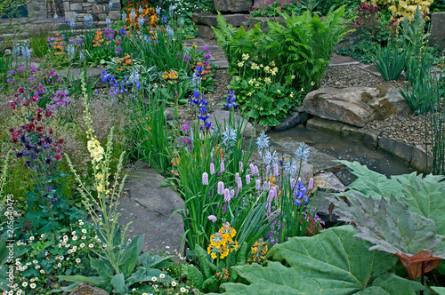 Leinwand Poster A country cottage and garden situated in a wooded rockery with a colourful displ