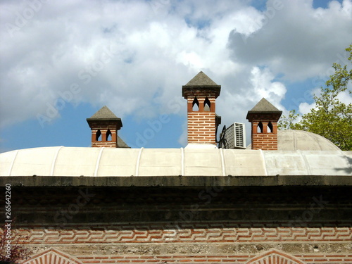 Nebengebäude der Großen Moschen mit kleinen Türmen vor blauem Himmel mit Wolken bei Sonnenschein in der alten osmanischen Hauptstadt Bursa am Uludag Gebirge in der Türkei photo