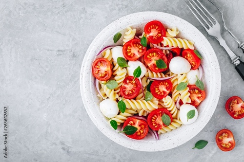 Italian pasta salad with tomatoes, mozzarella cheese, red onion and basil. Top view.