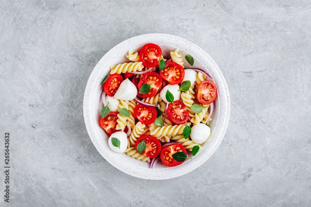 Italian pasta salad with tomatoes, mozzarella cheese, red onion and basil. Top view. Italian pasta salad with tomatoes, mozzarella cheese, red onion and basil. Top view.