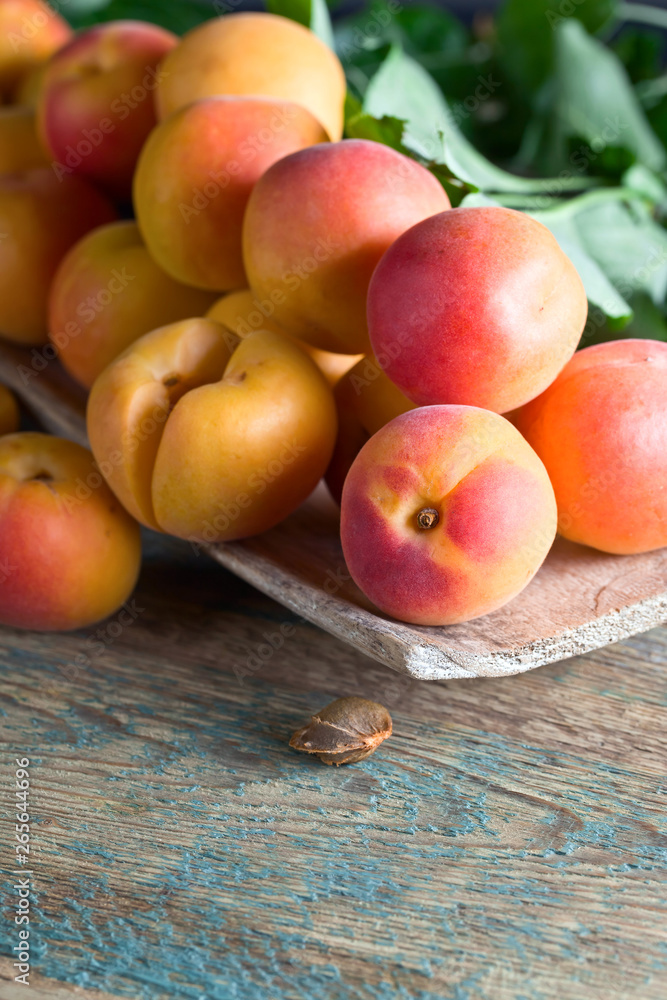 Apricots with leaves on old wooden table . Apricots with leaves on old wooden table .