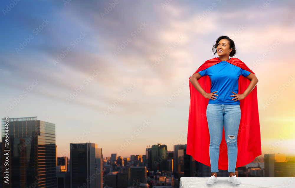 super power and people concept - happy african american young woman in superhero red cape on roof top over sunset in tokyo city background
