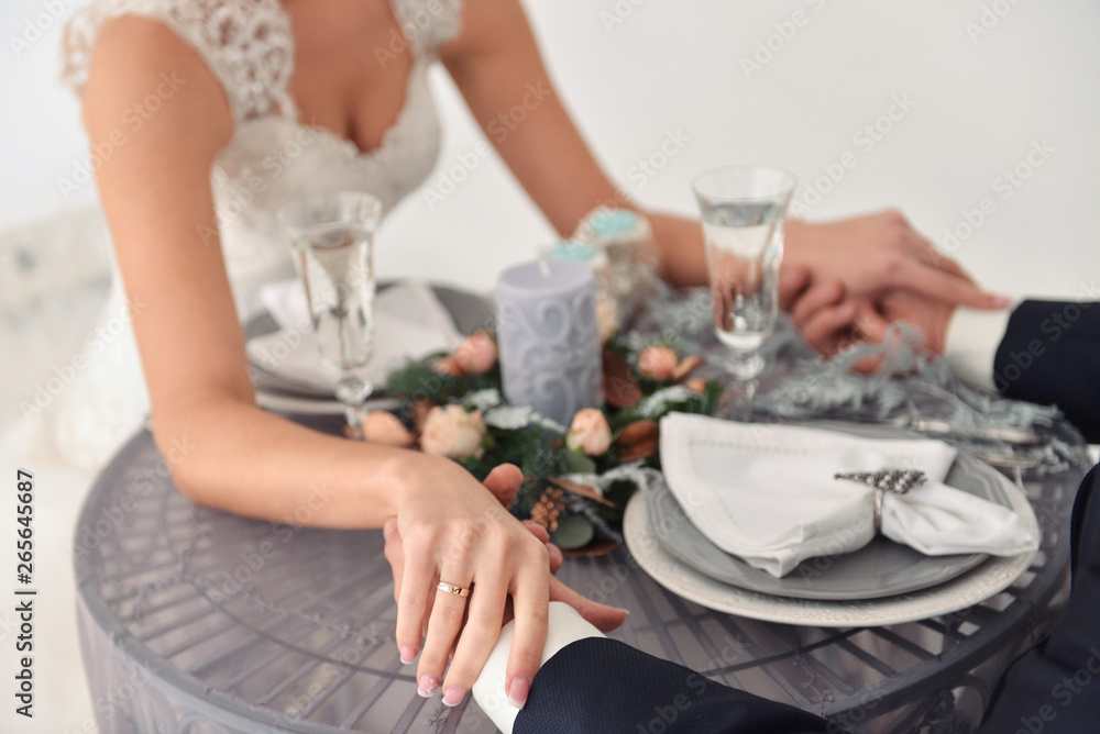 wedding couple of young people bride and groom, holding hands, enjoying a delicious meal together, served table close up view