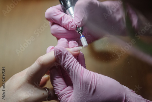 Manicurist makes hardware manicure close-up. Treatment of nails with the help of hardware manicure