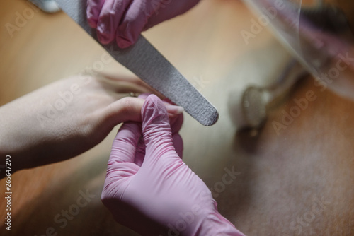 Manicurist handles nails with a nail file.