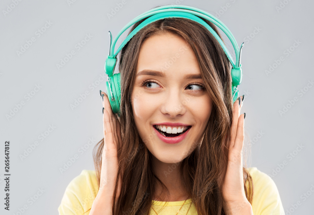 music, technology and people concept - happy young woman or teenage girl with headphones over grey background music, technology and people concept - happy young woman or teenage girl with headphones over grey background