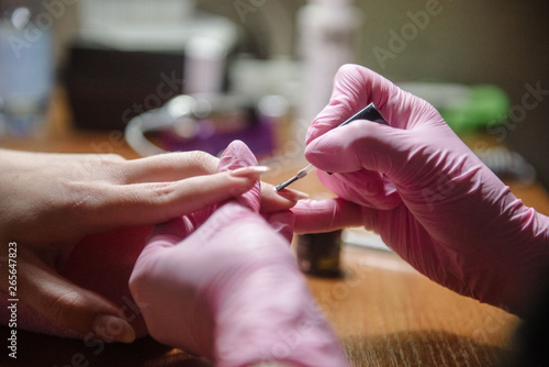 Manicurist applies varnish on the nail close up