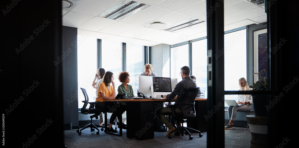 Creative business team working together in a casual office, seen from doorway, low angle Creative business team working together in a casual office, seen from doorway, low angle