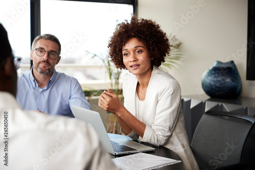 Millennial black businesswoman listening to colleagues at a corporate business meeting, close up