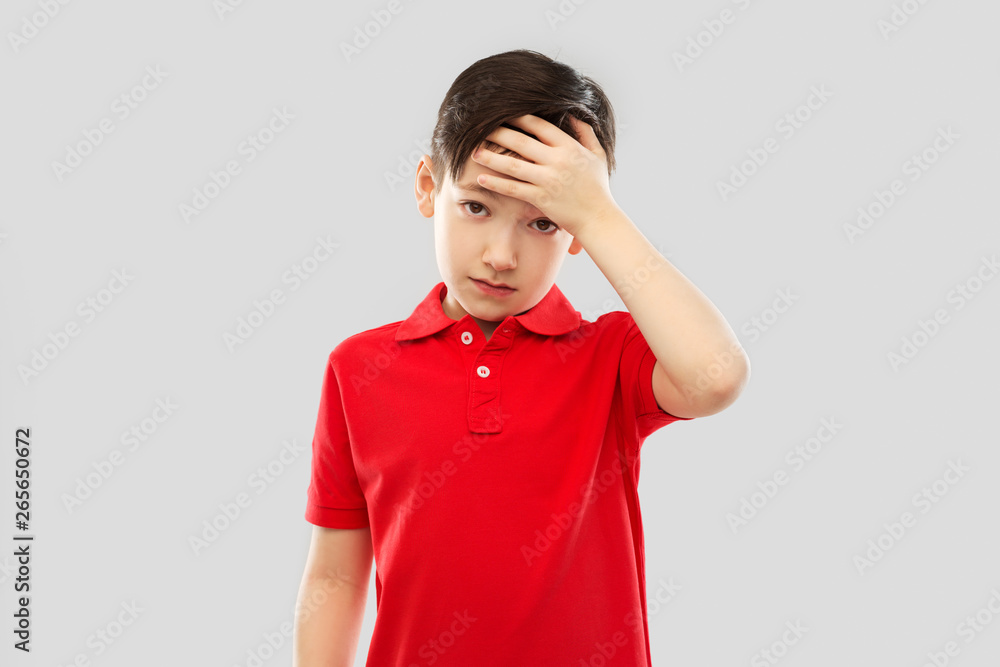 childhood, expressions and people concept - sick little boy in red polo t-shirt suffering from headache over grey background childhood, expressions and people concept - sick little boy in red polo t-shirt suffering from headache over grey background
