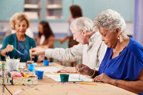 Group Of Retired Seniors Attending Art Class In Community Centre With Teacher