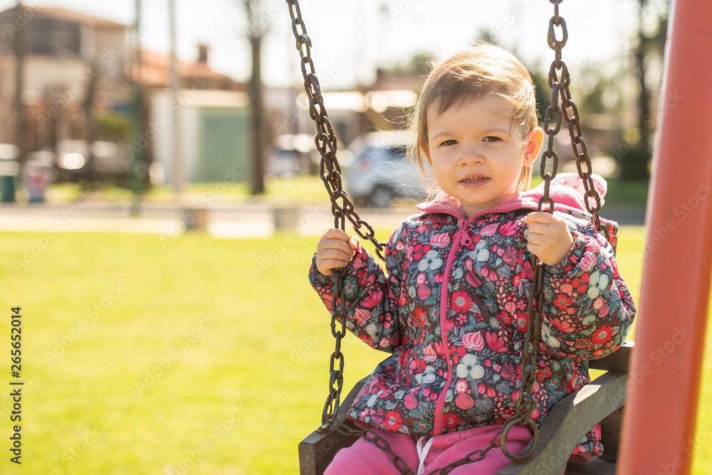 niña rubia juega parque hamaca plaza verde