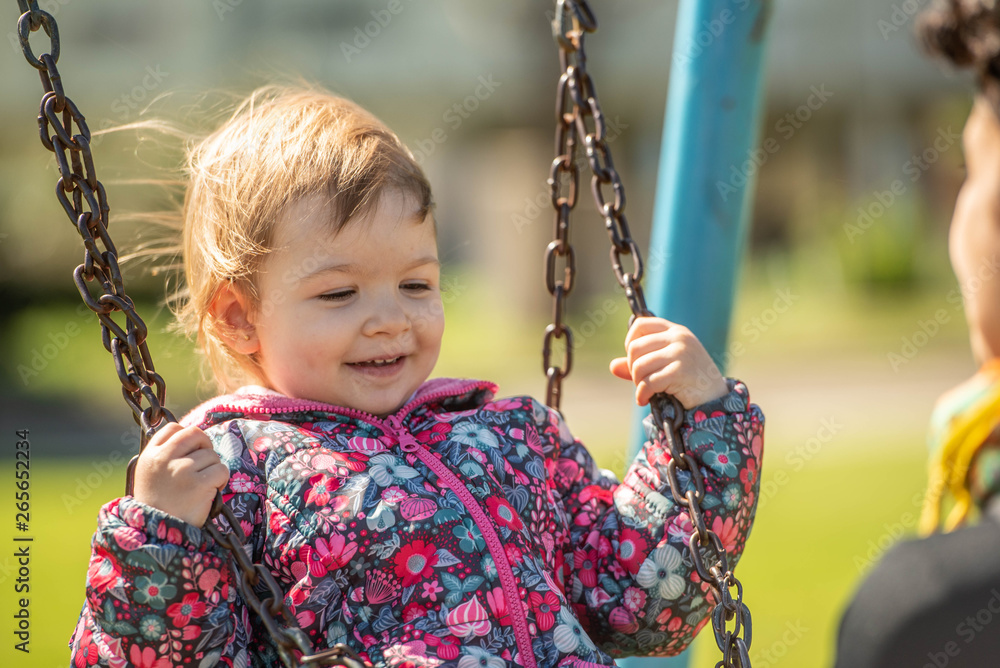 niña rubia juega parque hamaca plaza verde foto de Stock | Adobe Stock