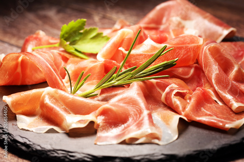 Italian prosciutto crudo or jamon with rosemary. Raw ham on wooden board