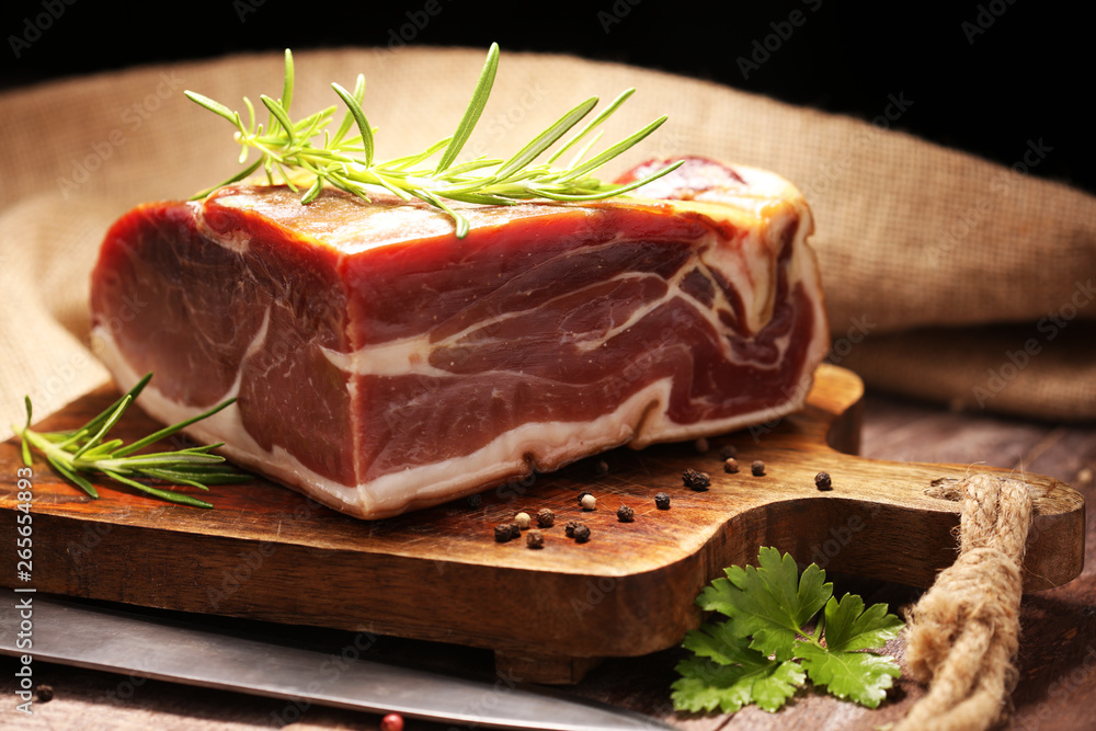 Italian prosciutto crudo or jamon with rosemary. Raw ham on wooden board Italian prosciutto crudo or jamon with rosemary. Raw ham on wooden board