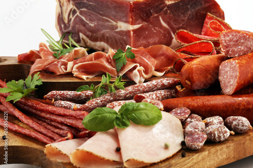 Food tray with delicious salami, pieces of sliced ham, sausages,salad and vegetable. Meat platter with selection