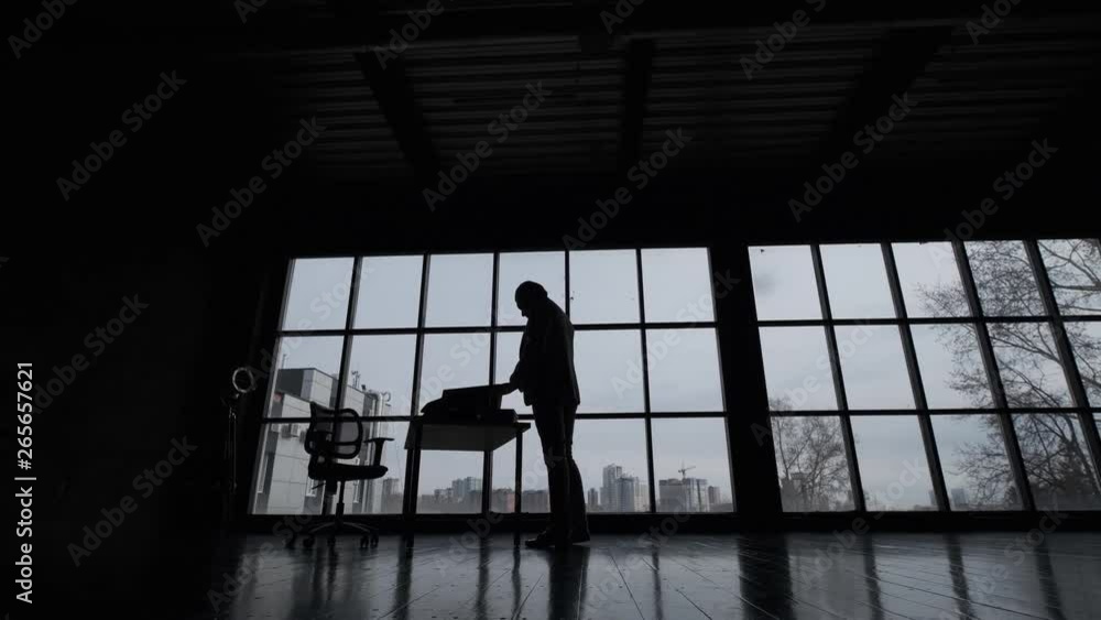 silhouette of a business man in the office against a large window in a spacious office silhouette of a business man in the office against a large window in a spacious office