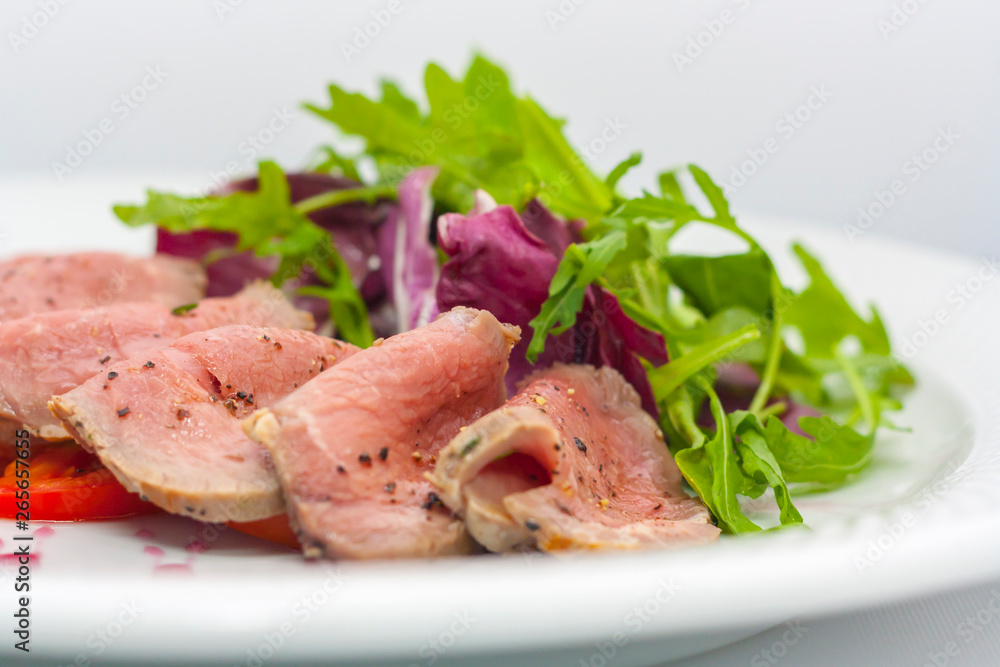 baked ham, cut into thin pieces, with spices, lettuce and tomato close-up baked ham, cut into thin pieces, with spices, lettuce and tomato close-up