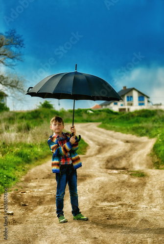 Portrait of a boy on a walk in the village with an umbrella .