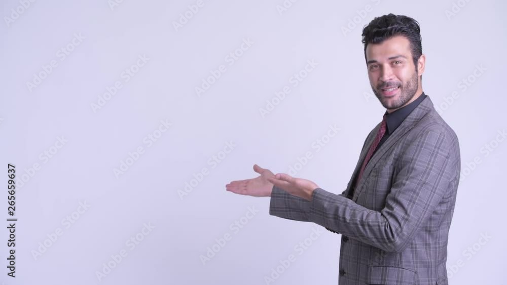 Happy bearded Persian businessman showing something to the back Happy bearded Persian businessman showing something to the back