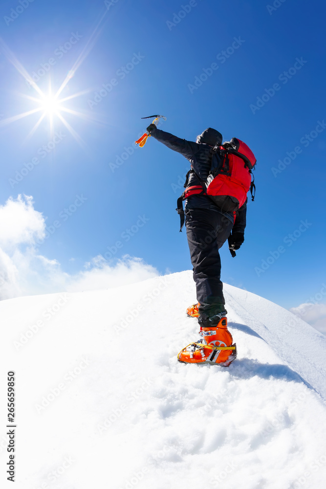 Φωτογραφία At the top: a lonely climber reaches the summit of a snowy mountain peak in winter season