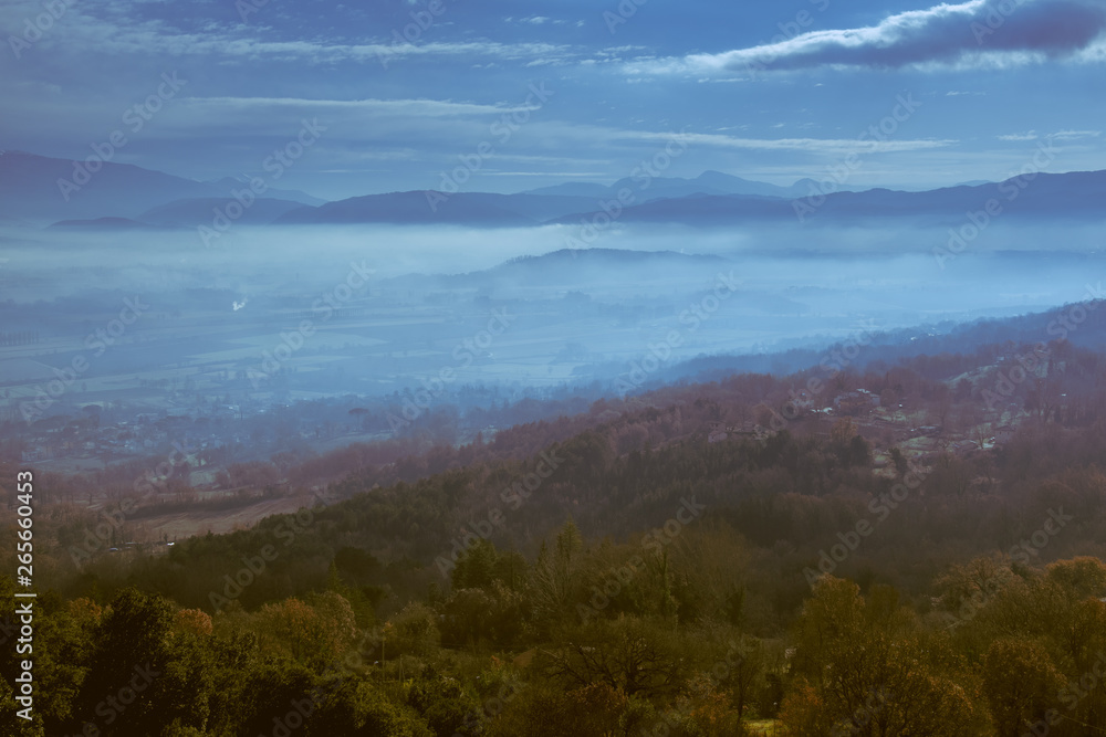 Panoramic view from a hill in the evening with low clouds over the valley
