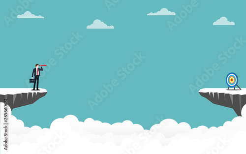 Businessman holding a binocular standing on cliff looking go to target