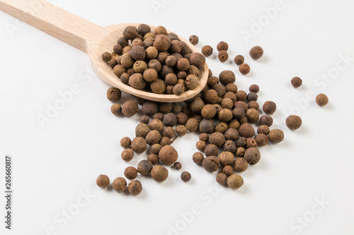 Allspice or Jamaican pepper on wooden spoon on white background