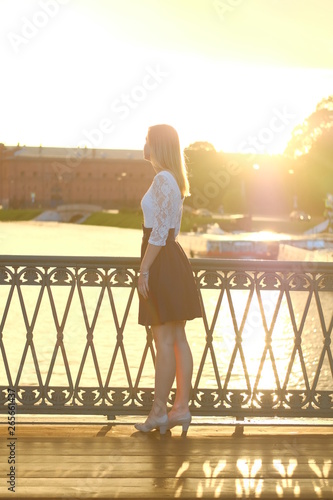 Beautiful blond girl in dress posing for photo at sunset