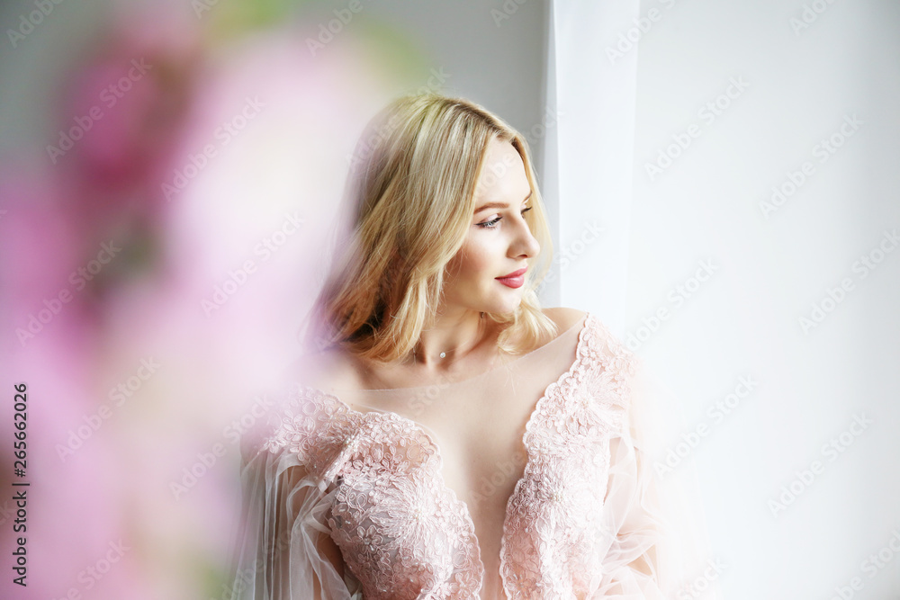 Young beautiful woman with blond wavy hairstyle wearing tender pink wedding dress. Fragile bride portrait in full length maxidress. Close up, copy space, background. Young beautiful woman with blond wavy hairstyle wearing tender pink wedding dress. Fragile bride portrait in full length maxidress. Close up, copy space, background.