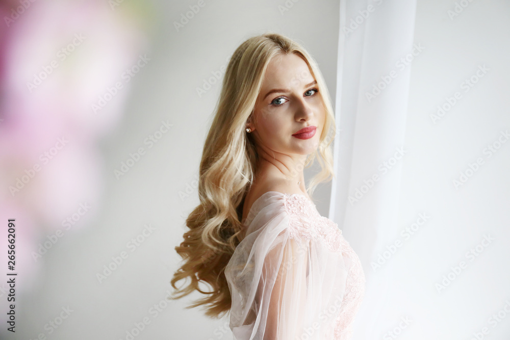 Young beautiful woman with blond wavy hairstyle wearing tender pink wedding dress. Fragile bride portrait in full length maxidress. Close up, copy space, background. Young beautiful woman with blond wavy hairstyle wearing tender pink wedding dress. Fragile bride portrait in full length maxidress. Close up, copy space, background.