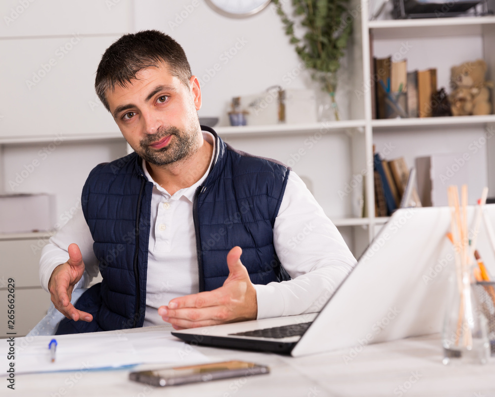 Naklejka premium Young man with laptop and papers working in office