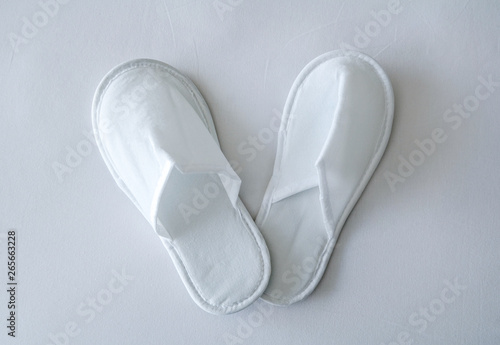 New white disposable hotel slippers on the background of white sheet