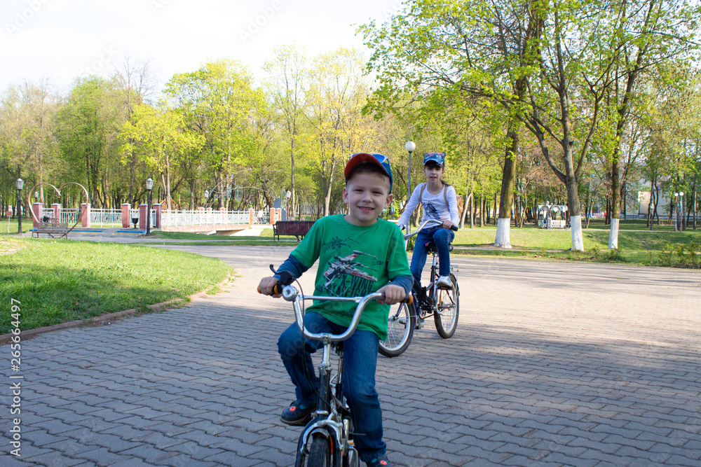 Obraz premium happy boy and girl ride bicycles in the park.