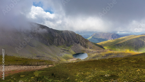 In the mountains of Snowdonia in North Wales on the way by train to the Snowdon overlooking a small lake and breathtakingly exciting clouds with pervading sunlight.