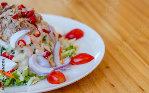 Spicy tuna salad In a white plate  salad this dish consist of tuna  lettuce  chinese cabbage  carrot onion red chilli rough cut  dressing and tomato half cut Used to arrange dishes.
