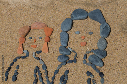 drawing a picture with stones of mother's day on sand on the beach.