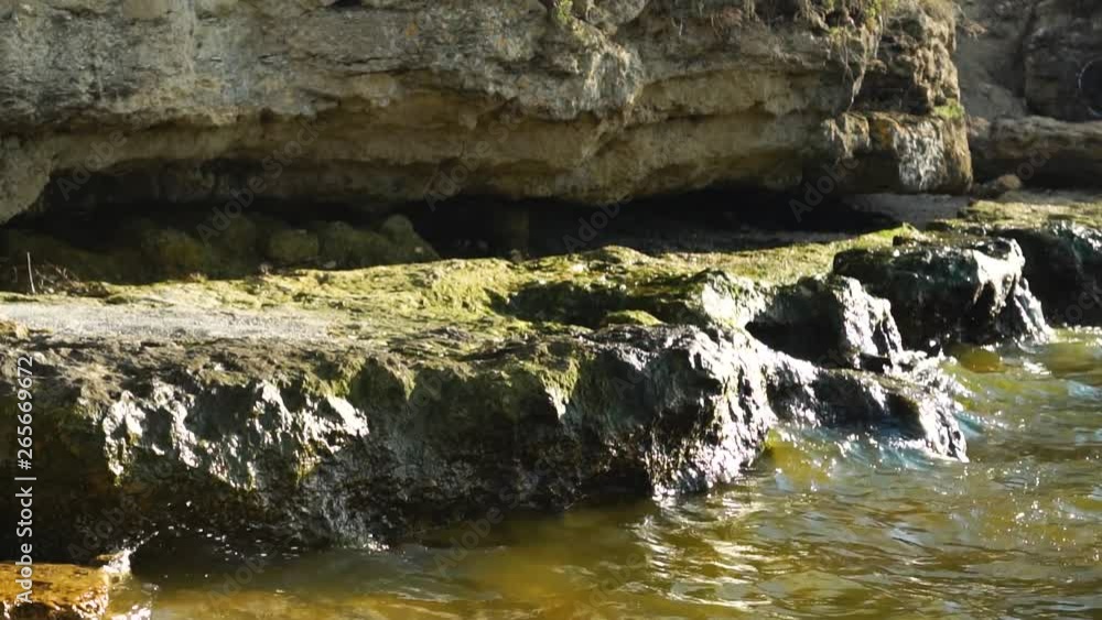 Time lapse steady view on spring stream small river waves crash against colorful stone rock beach on sunny nature day Time lapse steady view on spring stream small river waves crash against colorful stone rock beach on sunny nature day