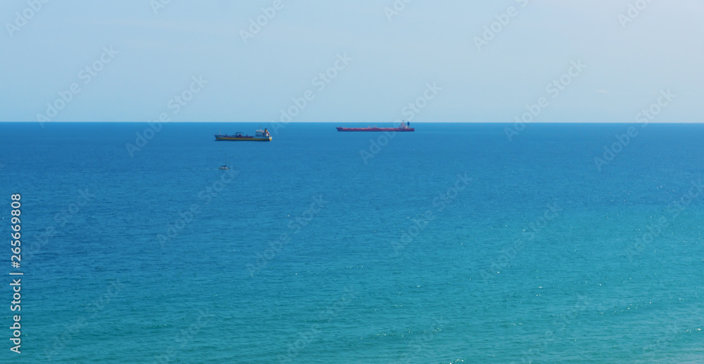 blue sea surface with small ships on the horizon