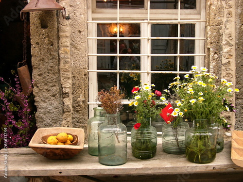 Vasen aus Glas mit Blumensträußen vor einem alten Laden und Geschäft mit Sprossenfenster in den Gassen der Altstadt von Alacati bei Cesme am Ägäischen Meer in der Provinz Izmir in der Türkei photo