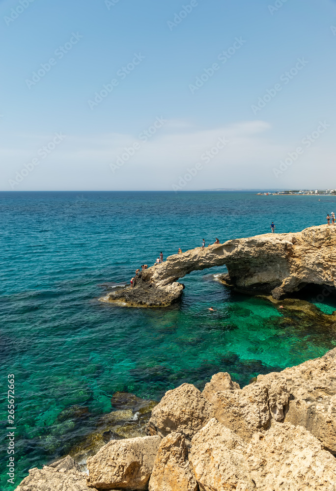 CYPRUS, THE BRIDGE OF LOVERS - MAY 11/2018: Tourists jump from a height into the azure waters of the Mediterranean Sea. CYPRUS, THE BRIDGE OF LOVERS - MAY 11/2018: Tourists jump from a height into the azure waters of the Mediterranean Sea.