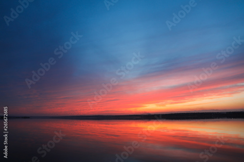 Dramatic sunset sky background with river  fiery clouds  yellow  orange and pink colour  nature background. Beautiful skies