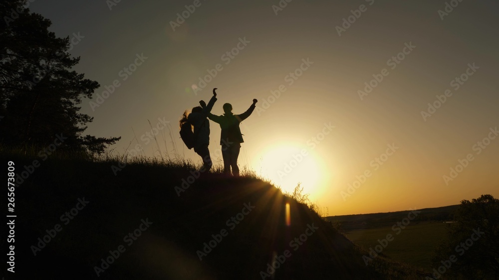 Hiker Girl Raising Her Hand Up, Celebrating Victory And Enjoying Scenery. mom and daughter on vacation traveling and dancing on mountain. Woman with raised hands on top of mountain looking at sunset
