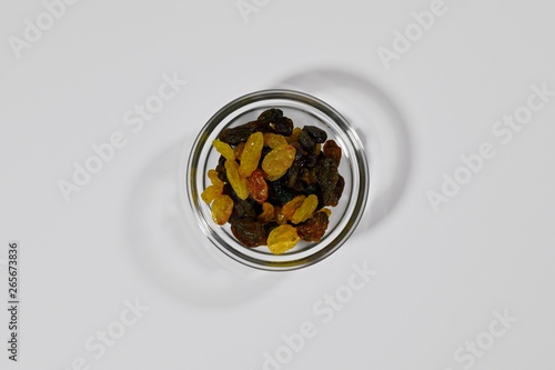 Assorted raisins, dark and light, in a round shape. Dried grapes in a small amount. Top view, centered, on a white background. photo