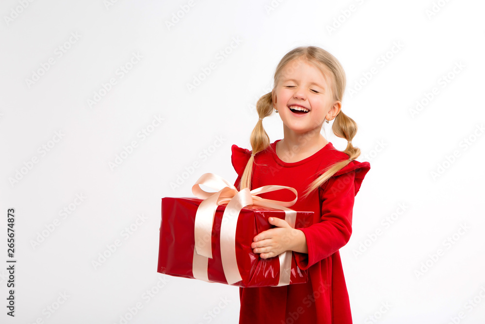 Portrait of little girl in red dress on isolated white background. Smiling Girl in shirt with gifts in hands looking at camera. Isolated gray background. The concept of celebrating, giving and receivi Portrait of little girl in red dress on isolated white background. Smiling Girl in shirt with gifts in hands looking at camera. Isolated gray background. The concept of celebrating, giving and receivi