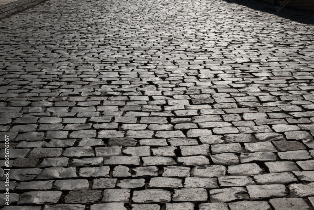 street is paved with cobblestones, paving stone background texture in the sun