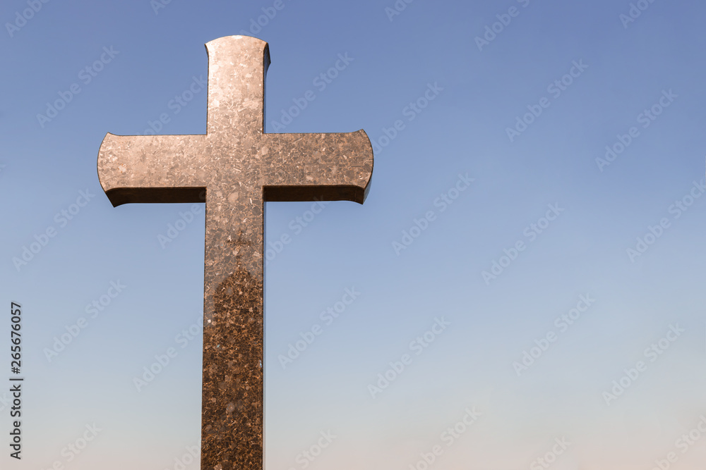 stone cross in a graveyard with copy space for text. crucifix against a blue sky background. stone cross in a graveyard with copy space for text. crucifix against a blue sky background.